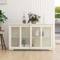 a vase with flowers is sitting on top of a white bookcase in the living room