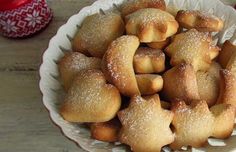 a white bowl filled with sugared pastries on top of a wooden table next to a christmas tree