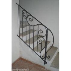 a wrought iron stair rail in an empty room with tile flooring and walls behind it