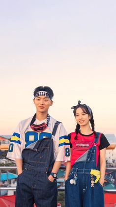 two people standing next to each other in overalls