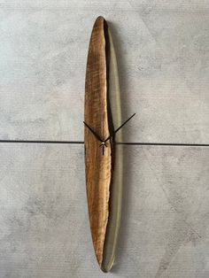 a clock made out of a piece of wood on the wall with black hands and an olive green band