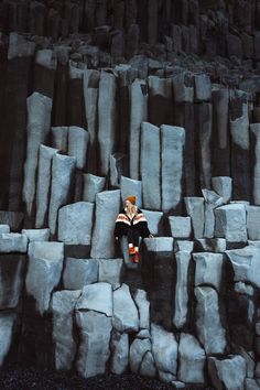 A woman sitting on Basalt Columns in Iceland during her road trip. Linked to a travel guide on How to Plan an Epic Iceland Road Trip.