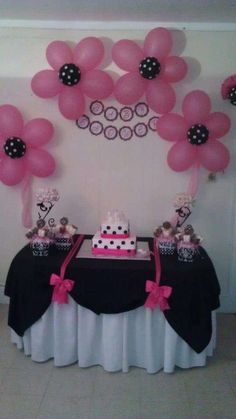 a table topped with pink and black balloons next to a cake on top of a table