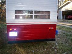 a red and white trailer parked in the grass