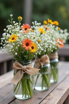 three mason jars filled with daisies and baby's breath