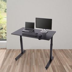 a computer desk with two monitors and a keyboard on it in front of a window