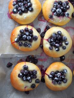 blueberry donuts with icing and blackberries on them sitting on wax paper