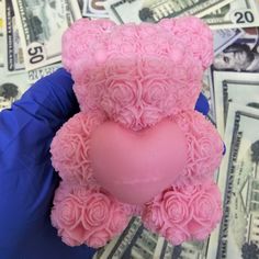 a pink teddy bear sitting on top of a pile of money with the shape of a heart