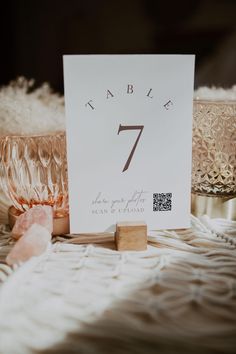 a table number is placed on top of a card next to some glass bowls and rocks