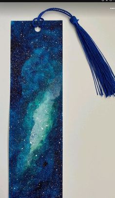 a bookmark with a blue tassel hanging from it's side on a table