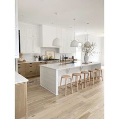 a large kitchen with white cabinets and wooden flooring, along with an island in the middle