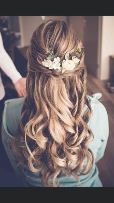 a woman with long blonde hair and flowers in her hair is shown from the back