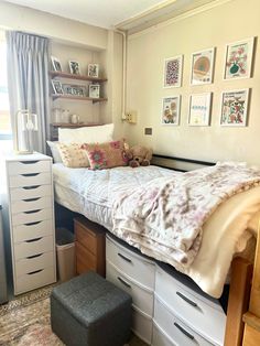 a bedroom with a bed, drawers and pictures on the wall next to a window