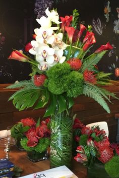 a vase filled with lots of flowers on top of a wooden table next to a book