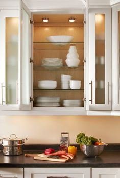 a kitchen with white cabinets and dishes in it