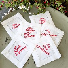 four embroidered napkins on a plate with flowers in the background