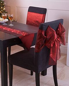 a dining room table decorated for christmas with red bows and wine glasses on the table