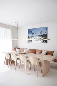 a dining room table and chairs in front of a painting on the wall above it