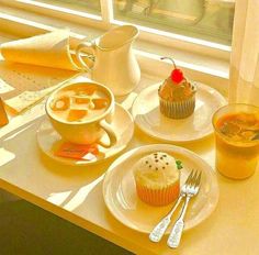 there is a cupcake, muffin and orange juice on the table by the window