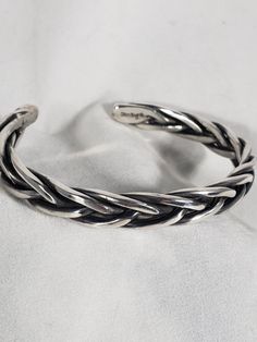 "Very classy sterling silver braided cuff. Completely hand made of five strands of 2.5mm (.100\") sterling silver round wire, braided, forged, formed and polished by me. It is approx. 3/8\" wide by 3/16\" thick.  It weighs in at  approx. 51 gr. (about 1.8 ounces) This is a substantial bracelet. Nothing flimsy about this cuff. It comes in various sizes. If you measure snugly (but not tight) around your wrist where you intend to wear it, that should be the measurement you want. There is about a one inch gap which should make it a comfortable fit. There is a black patina that is only noticeable in the recesses but gives a dimensional look. If you prefer it without patina please leave a note with your order." Silver Braided Bracelet, Braid Cuffs, Love Knot Ring, Erie Pa, Braided Bracelet, Wide Rings, Braided Bracelets, Silver Cuff, Making Jewelry