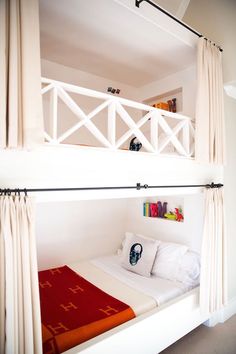 there is a bunk bed with curtains on the top and bottom level above it in this bedroom