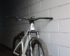 a white bicycle parked against a brick wall