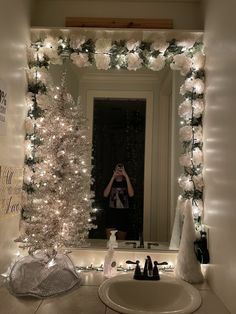 a woman taking a selfie in front of a mirror with christmas lights on it