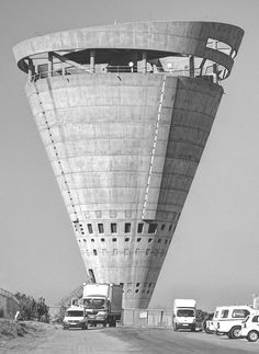 several trucks are parked in front of a tall building that is shaped like a cone