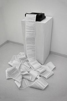 a pile of papers sitting on top of a floor next to a tall white box