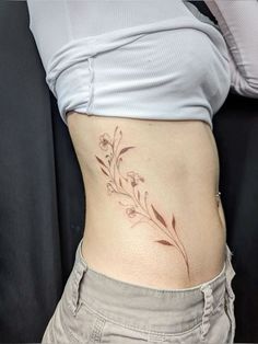 a woman's stomach with a flower tattoo on her side and the bottom part of her belly