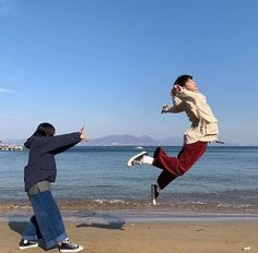 two people jumping in the air on a beach