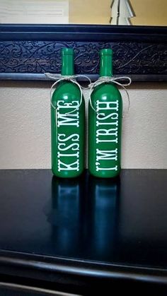 two green bottles sitting on top of a black table next to each other with white writing