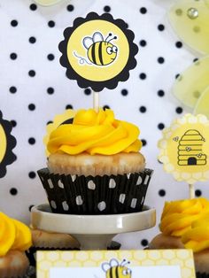 a table topped with cupcakes covered in yellow frosting next to honey signs