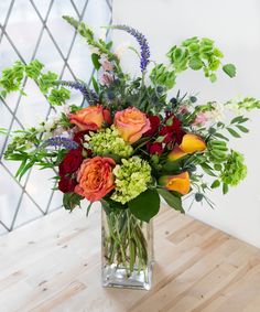 a vase filled with lots of flowers on top of a wooden table