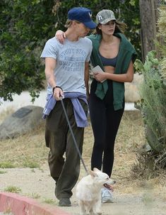 a man and woman walking their dog on a leash