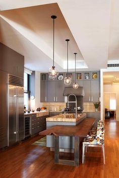 a large kitchen with wooden floors and stainless steel appliances, along with an island in the middle