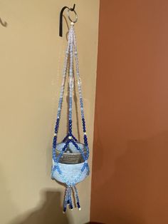 a hanging planter made out of beads and glass beads with a hook on the wall