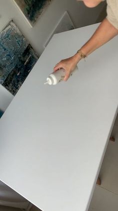 a person using a spray bottle to paint a table