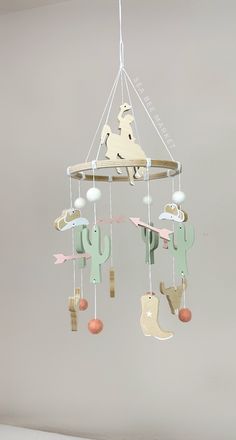 a baby mobile with horses and cactuses hanging from it's hooks in a nursery room