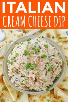 a bowl filled with cream cheese dip surrounded by crackers and parsley on an orange background