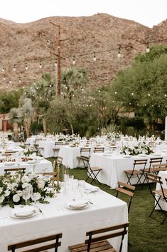 an outdoor wedding reception setup with white tablecloths and floral centerpieces in the desert