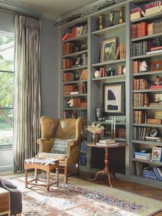 a living room filled with lots of bookshelves next to a chair and table