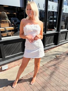 a woman in a short white dress posing for the camera with her hand on her hip