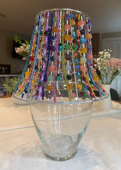 a table with a lamp made out of glass beads and colorful bead necklaces