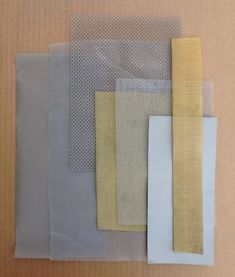 several different colors of fabric sitting on top of a cardboard box with one yellow and the other gray