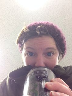 a woman is drinking from a can in front of her face and looking at the camera