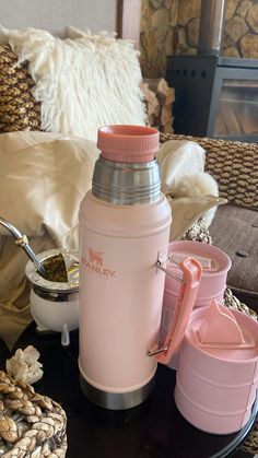 a pink water bottle sitting on top of a table next to two cups and a spoon