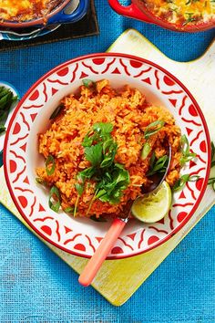 a bowl of rice with cilantro and lime on the side next to another dish