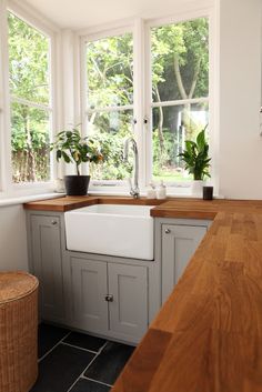 a kitchen filled with lots of windows next to a sink and wooden counter top under a window