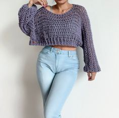 a woman in blue jeans and a purple knitted sweater is posing for the camera